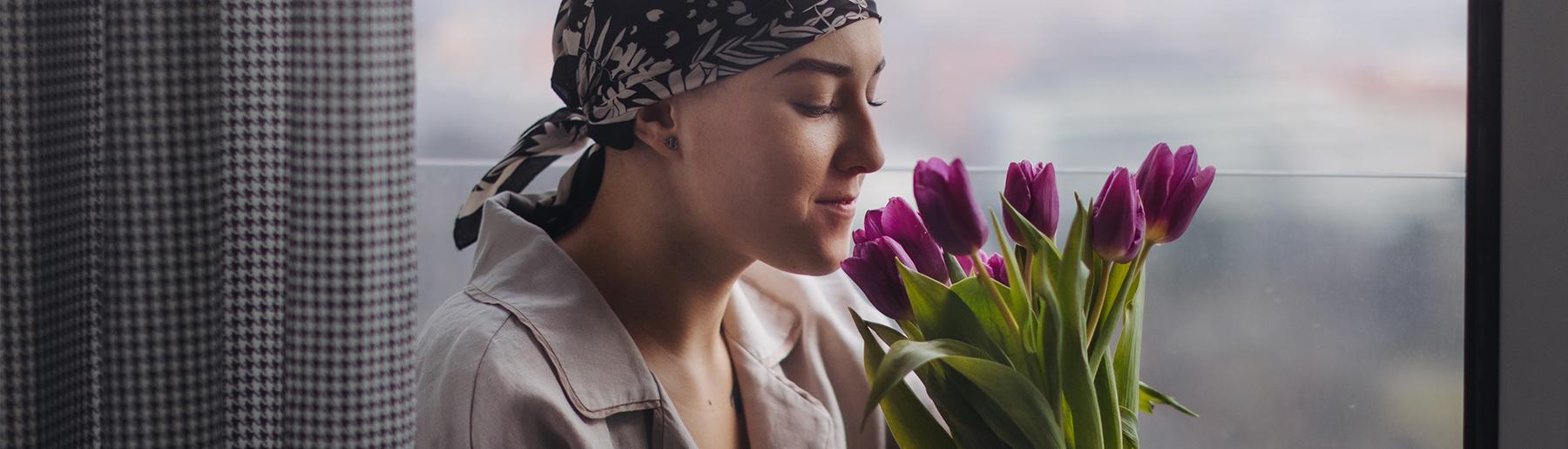 Vrouw met kanker ruikt aan tulpen
